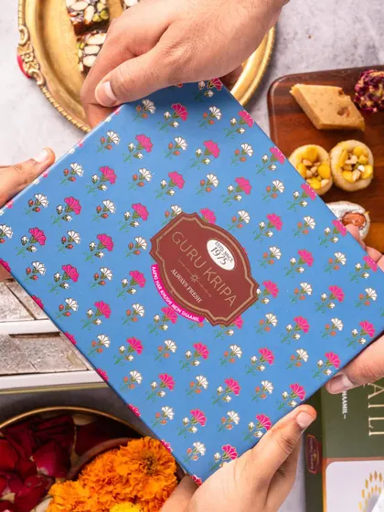The act of gifting is central to many festivals. This photo captures the exchange of a beautifully packaged box of sweets, creating a relatable and aspirational moment for a Rakhi campaign.