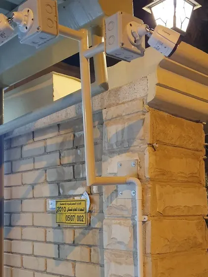 A multi-camera setup on a brick wall entrance, providing security coverage for the gate and surrounding area at night.