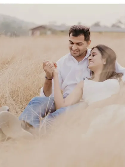 A quiet moment of connection in a field of golden grass. The soft, diffused light of the setting sun creates a warm, rustic, and incredibly romantic atmosphere for this pre-wedding portrait.