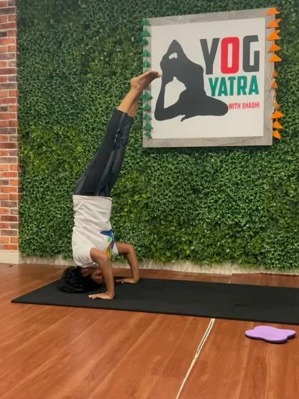 A perfect Sirsasana (Headstand) in front of our studio logo. This pose is a cornerstone of our practice for building focus and strength.