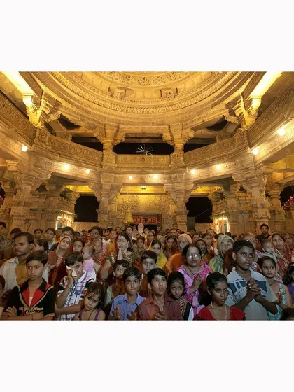 A large congregation of devotees gathered inside a grand temple hall. This photograph captures the scale of the community and the shared focus of their devotion during a religious event.