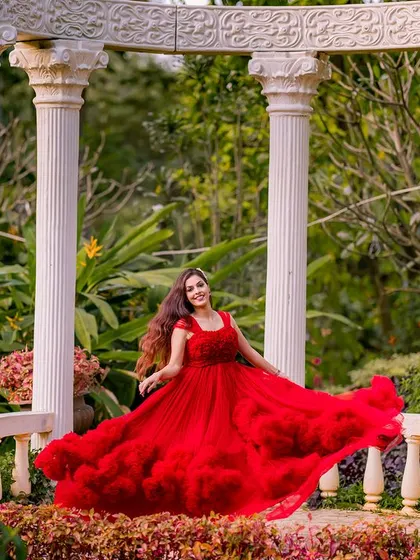 A joyful and energetic portrait. The bride-to-be twirls in her ruffled red gown, creating a beautiful shape against the backdrop of the classic white pillars.