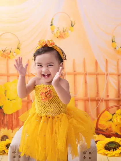 A little ray of sunshine. This baby girl's joyful laugh is the centerpiece of this bright and cheerful sunflower-themed shoot.