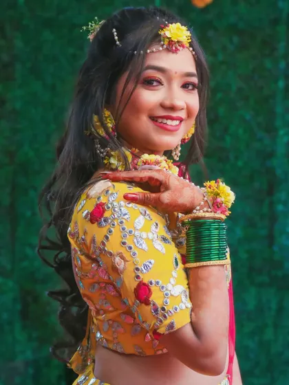 A playful and happy portrait of the bride during her pre-wedding festivities, showing off her floral accessories and henna.
