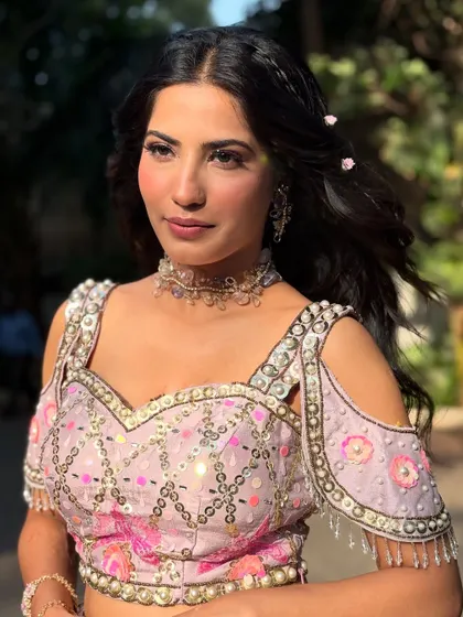 This look is all about effortless charm. The soft lighting highlights the dewy finish of her skin and the intricate details of her outfit.