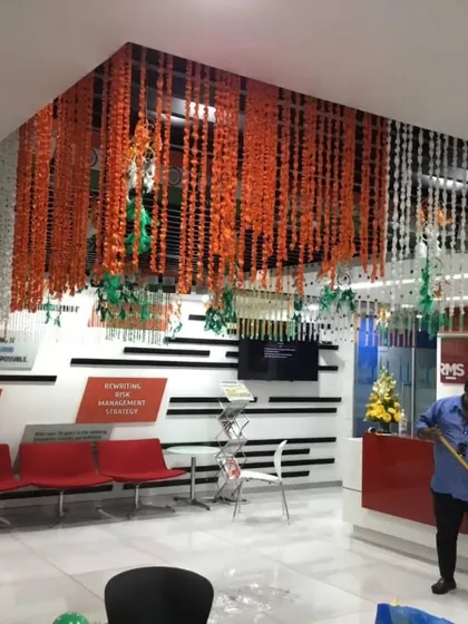 An office reception area transformed with a ceiling installation of saffron, white, and green flower garlands. This is an elegant way to bring the national colors into a corporate space for Independence Day.