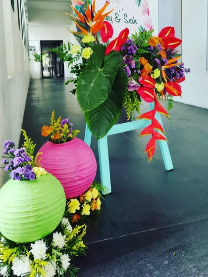 A welcome sign for the 'Colour Pop' brunch, set on a mint green easel and adorned with a burst of tropical, colorful flowers.