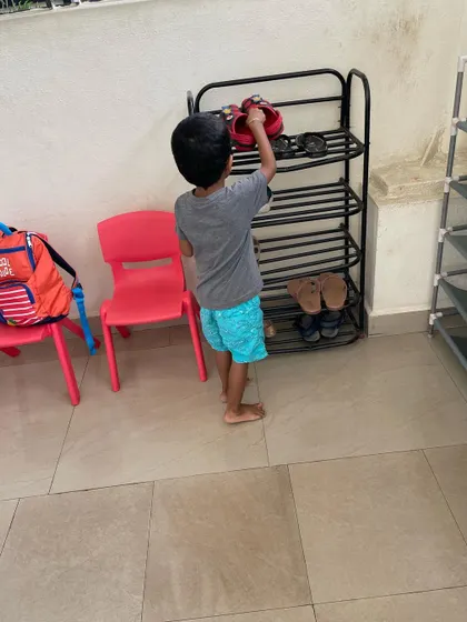 A child learns to manage their belongings, from taking off their shoes and putting them on the rack to getting their own bag. These simple routines are the building blocks of responsibility and independence.