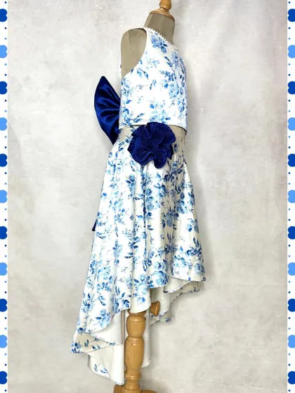 Another view of our blue floral high-low skirt set, showing the dramatic bow and flower detail that makes it a true showstopper for any daytime event.