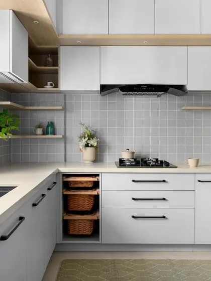 A clean and minimalist kitchen design with grey cabinets, a matching square tile backsplash, and light wood open shelving.