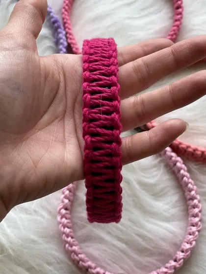 A close-up view of a vibrant magenta macrame hairband held in my hand. This angle highlights the consistent, tight knotting I use to create a durable and comfortable hair accessory.