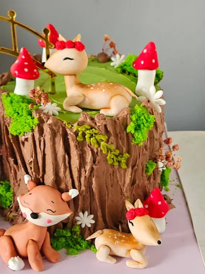A detail shot of the other side of the woodland cake, featuring a gentle deer and other cute forest creatures. The red edible mushrooms add a pop of color.