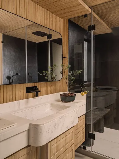 The master bathroom at Kanso House features a custom marble sink and wood-paneled walls, creating a warm, spa-like atmosphere.
