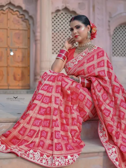 A beautiful seated portrait on the steps of the heritage building. The red saree drapes elegantly around her, creating a regal and timeless image.
