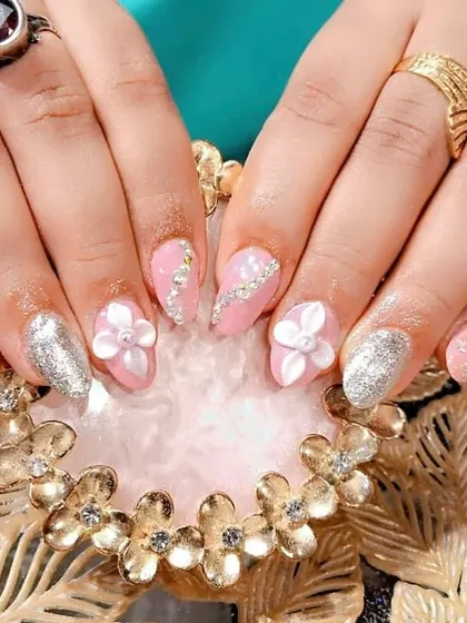 A pretty-in-pink set with silver glitter accent nails, 3D white flowers, and delicate silver stone detailing.