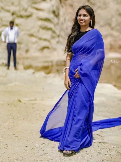 A beautiful portrait of the bride-to-be in a flowing blue saree, with the groom in the background. This creates a lovely sense of depth and story.