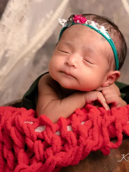 A sweet smile from this little one in the strawberry-themed shoot. This close-up captures a moment of pure, sleepy joy.