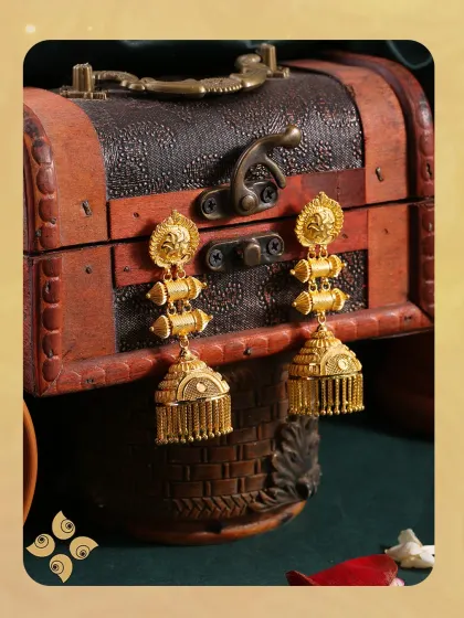 Elevate every look with our stunning gold jhumkis. These traditional earrings feature a classic bell shape with delicate fringe, set against a rich, antique-style background.