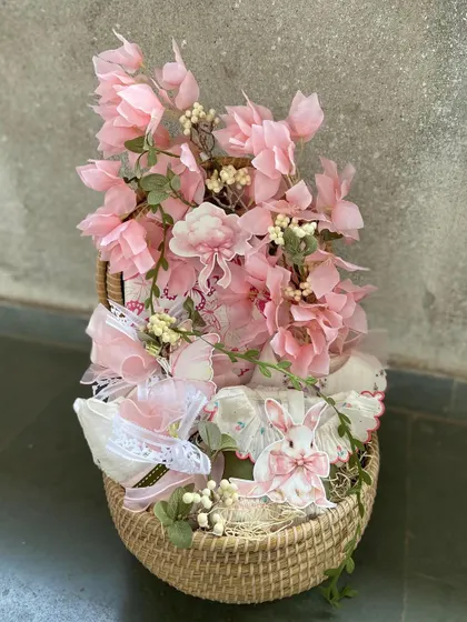 A delicate and pretty-in-pink baby girl hamper. This basket is overflowing with soft pink florals and lace-trimmed baby items, making it a timeless and elegant gift.