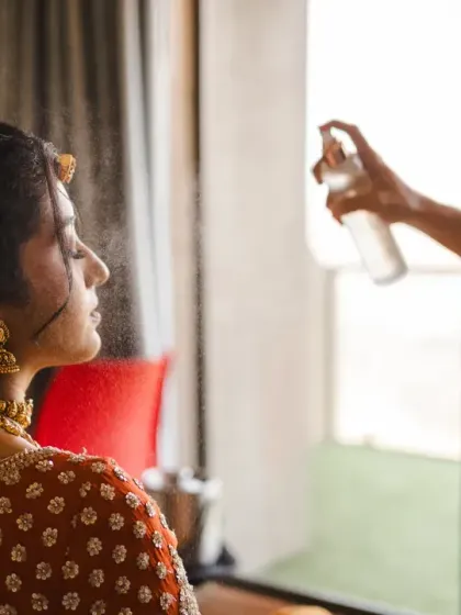 A close-up of the bride getting her makeup setting spray applied. This behind-the-scenes shot captures the final moments of her transformation into a bride.
