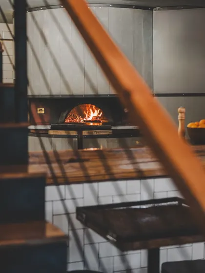 A glimpse of our wood-fired oven from the stairs. It's the heart of our kitchen and the source of all our delicious pizzas.