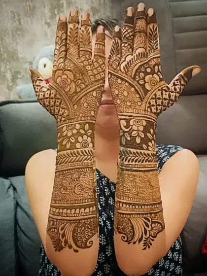Full-coverage mehandi on the back of the hands, featuring a mix of floral, paisley, and geometric patterns that flow from the fingers to the forearms.