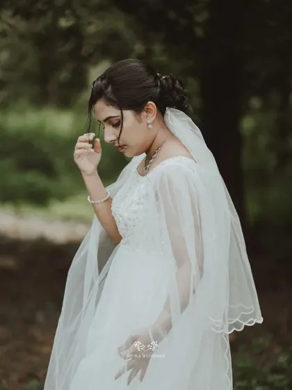 A pensive and beautiful portrait of the bride in a natural, wooded area, her veil gently draped.