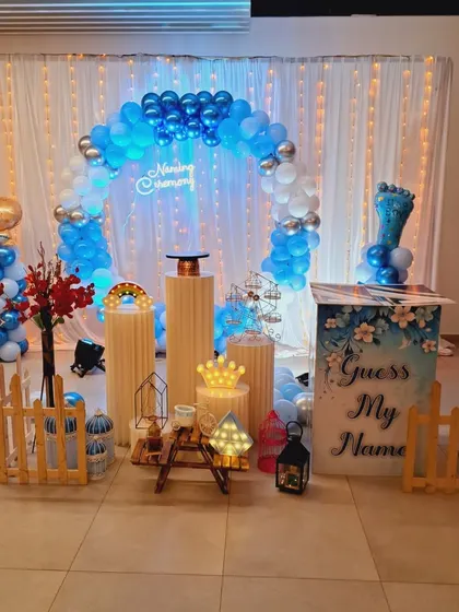 The complete view of the blue-themed naming ceremony stage, showing the balloon arch, neon sign, and various decorative props like lanterns and a miniature Ferris wheel.