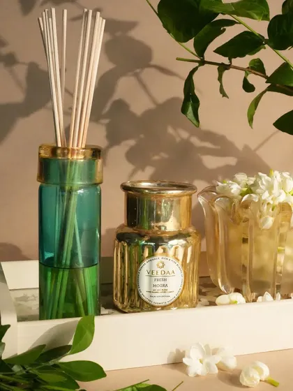 The delicate scent of Fresh Mogra, captured in our reed diffuser and a small golden candle. This setup on a white tray with fresh jasmine flowers is the picture of elegance and serenity.