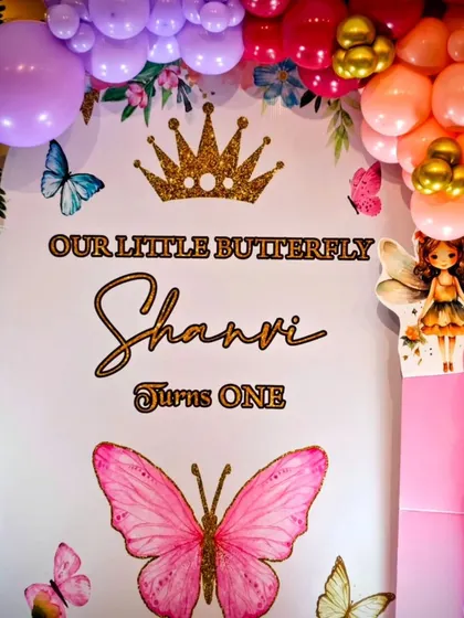 The 'Our Little Butterfly' welcome backdrop for Shanvi's first birthday, framed by a colorful balloon arrangement.