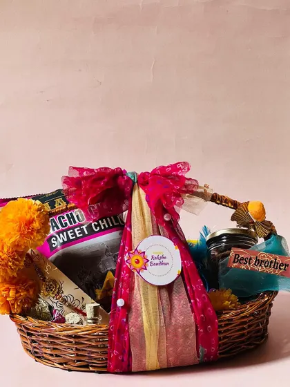 A single, beautifully wrapped Rakhi basket, decorated with marigold pom-poms and a traditional cloth wrap.