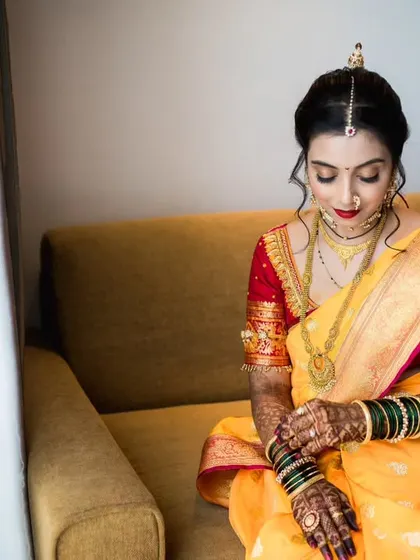 A serene moment captured as the bride gets ready. She looks down at her hands, showcasing the intricate mehndi and traditional green bangles.