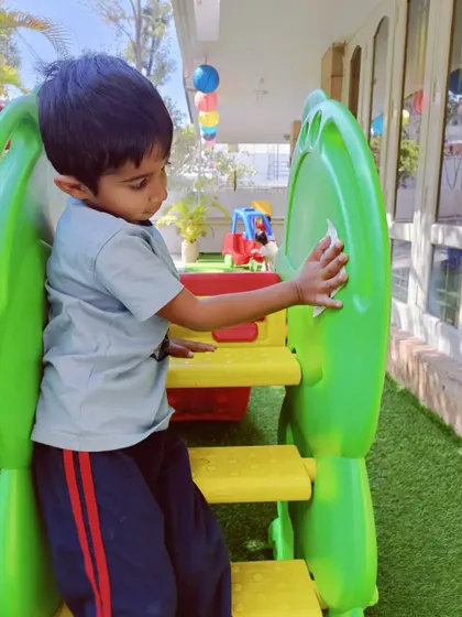 A child carefully cleaning the slide. Learning to clean up is a valuable lesson in responsibility and respect for their environment.