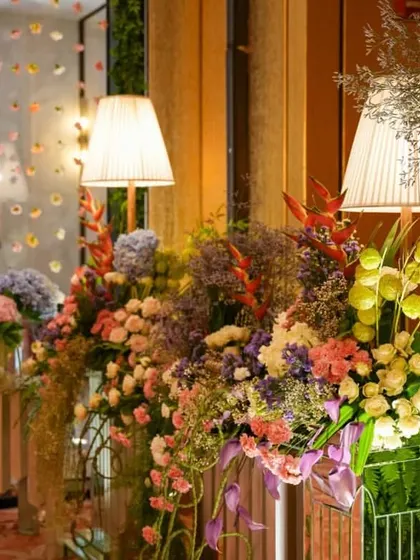 A close-up of the pastel floral arrangements, showing the beautiful mix of colors and textures. The soft lighting from the table lamps adds a touch of warmth to the daytime setup.
