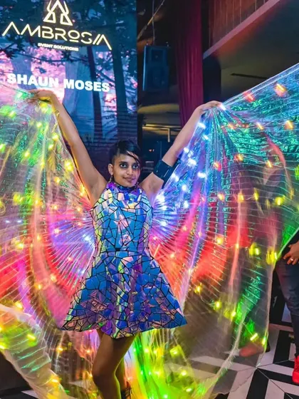 A vibrant shot from a pixel LED show at Raahi, performing alongside the DJ. The colorful LED wings and mirrored dress create a dazzling, high-energy look.