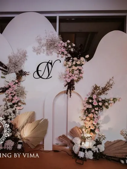 A classic and elegant reception setup symbolizing everlasting love. The stage features a modern, minimalist backdrop with custom monograms, floral arrangements, and soft lighting.