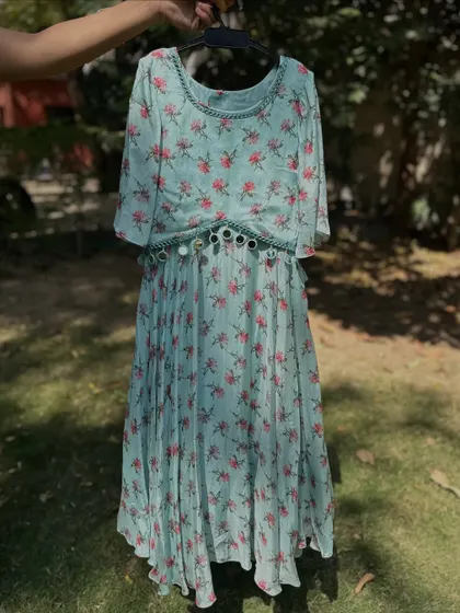 This floral dress in a soft mint color is perfect for summer parties. It features a pleated skirt and a mirror-work belt, adding a touch of festive sparkle to a comfortable design.