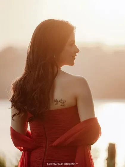 A beautiful back profile of the bride in her red gown, looking out at the sea during the golden hour.