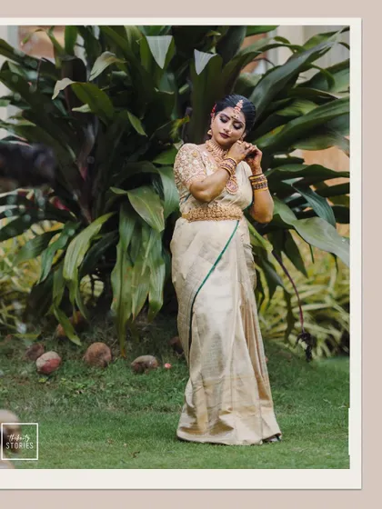 The bride adjusting her earring, captured in a full-length shot against a lush green background, showcasing her complete bridal look.