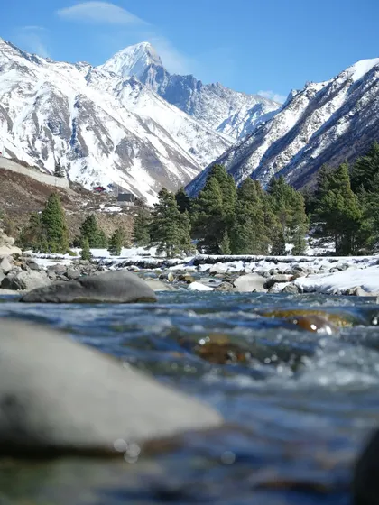 A series of photos capturing the serene beauty of a river flowing through a snow-lined valley. The long-exposure shot creates a milky effect on the water, contrasting with the sharp peaks.