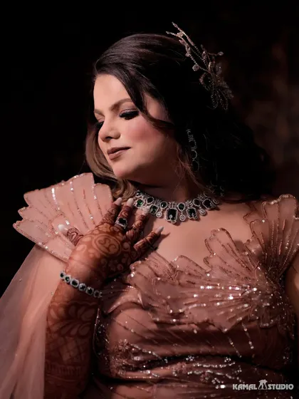 A portrait of the bride looking down, showcasing her elegant gown, hairstyle, and intricate henna design.