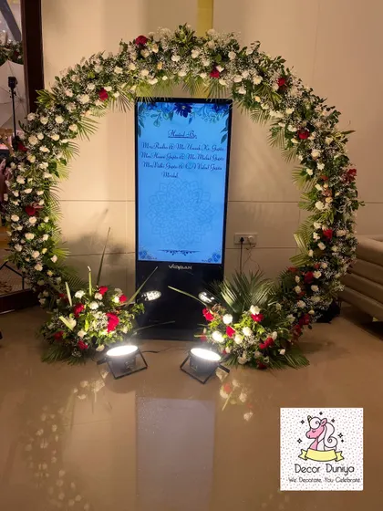 A modern and interactive welcome for your guests. This digital welcome screen is framed by a beautiful circular floral arch, combining technology with classic decor.