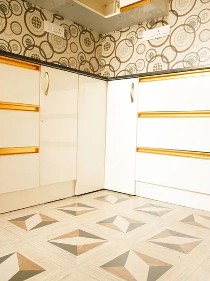 A low-angle shot highlighting the unique floor tiles that match the backsplash, a bold design choice that pays off. The gold profile handles on the white cabinets tie the look together.