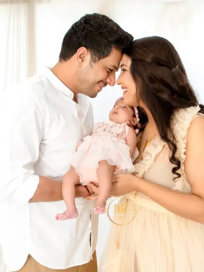 A light and airy newborn family portrait. The family is dressed in soft, neutral colors against a bright white background for a fresh and timeless feel.