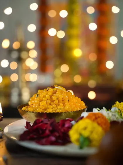 A bowl of boondi against a backdrop of diyas and flowers. The shallow depth of field and twinkling lights create a beautiful, dreamy atmosphere for this festive shot.