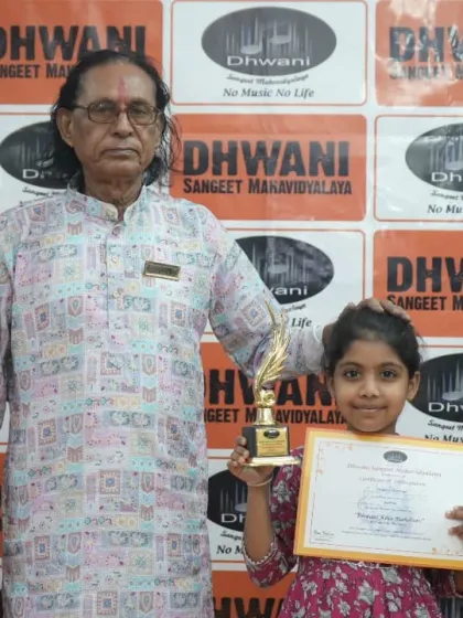 A senior guru blesses his young student as she holds her award.