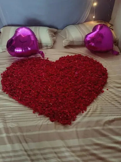 A close-up of the heart made from fresh rose petals on the bed. It's a classic touch for a romantic room decoration.