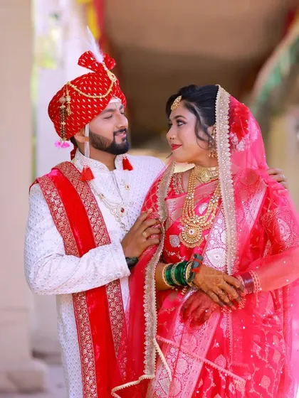 A loving glance between the bride and groom. The groom's traditional Maharashtrian wedding attire is perfectly complemented by his flawless makeup.