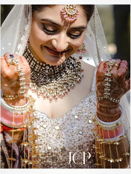A close-up of the bride's intricate jewelry and henna-adorned hands.