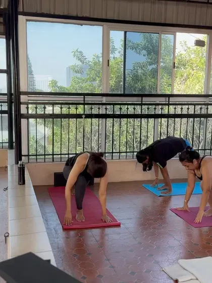 A view of students in a forward lunge, working on hip flexibility and leg strength. Our studio provides a bright and open space to focus on your personal practice within a supportive community.